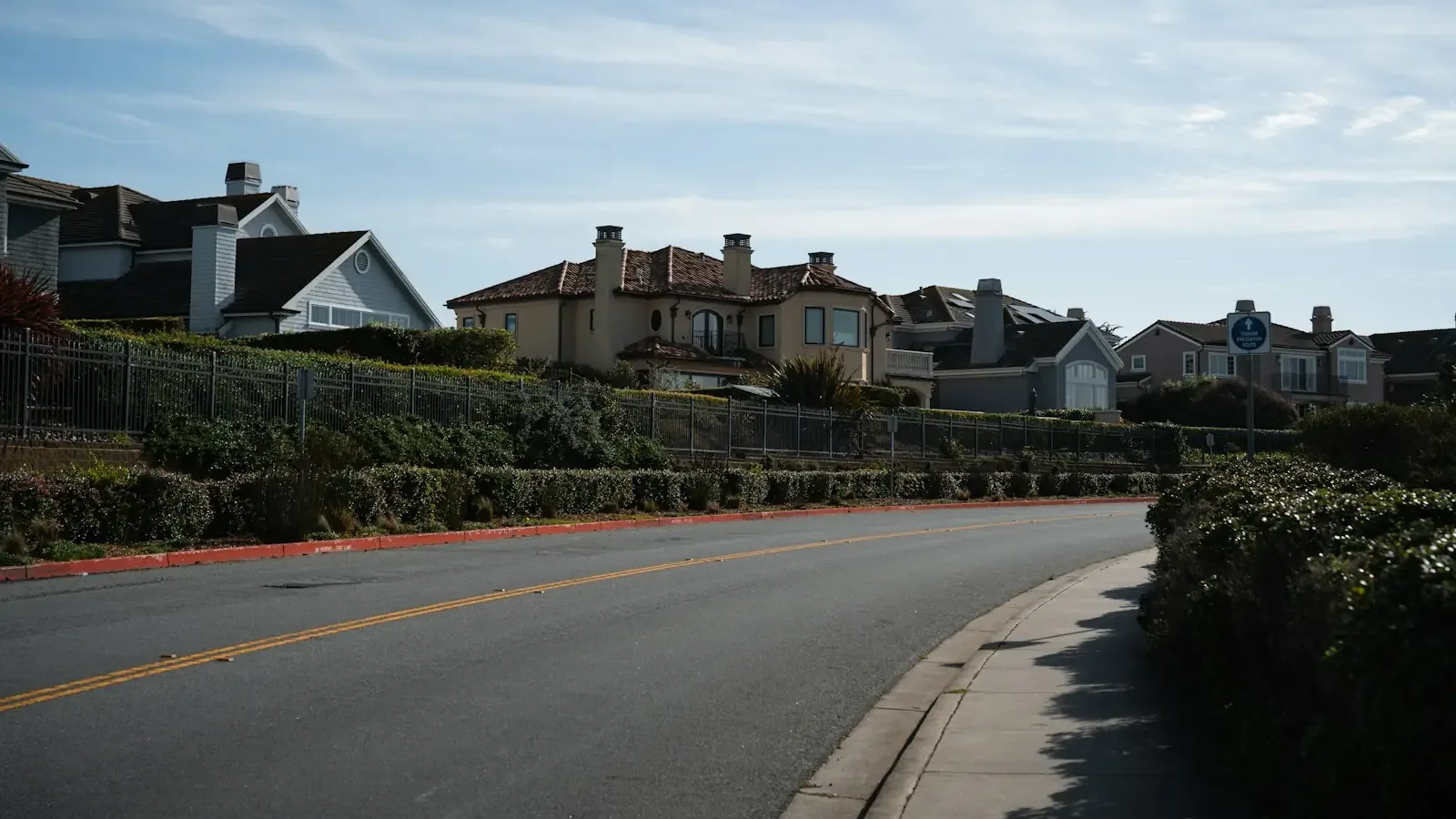 A curving suburban street lined with tile-roofed houses on a planned tract in Lake Forest