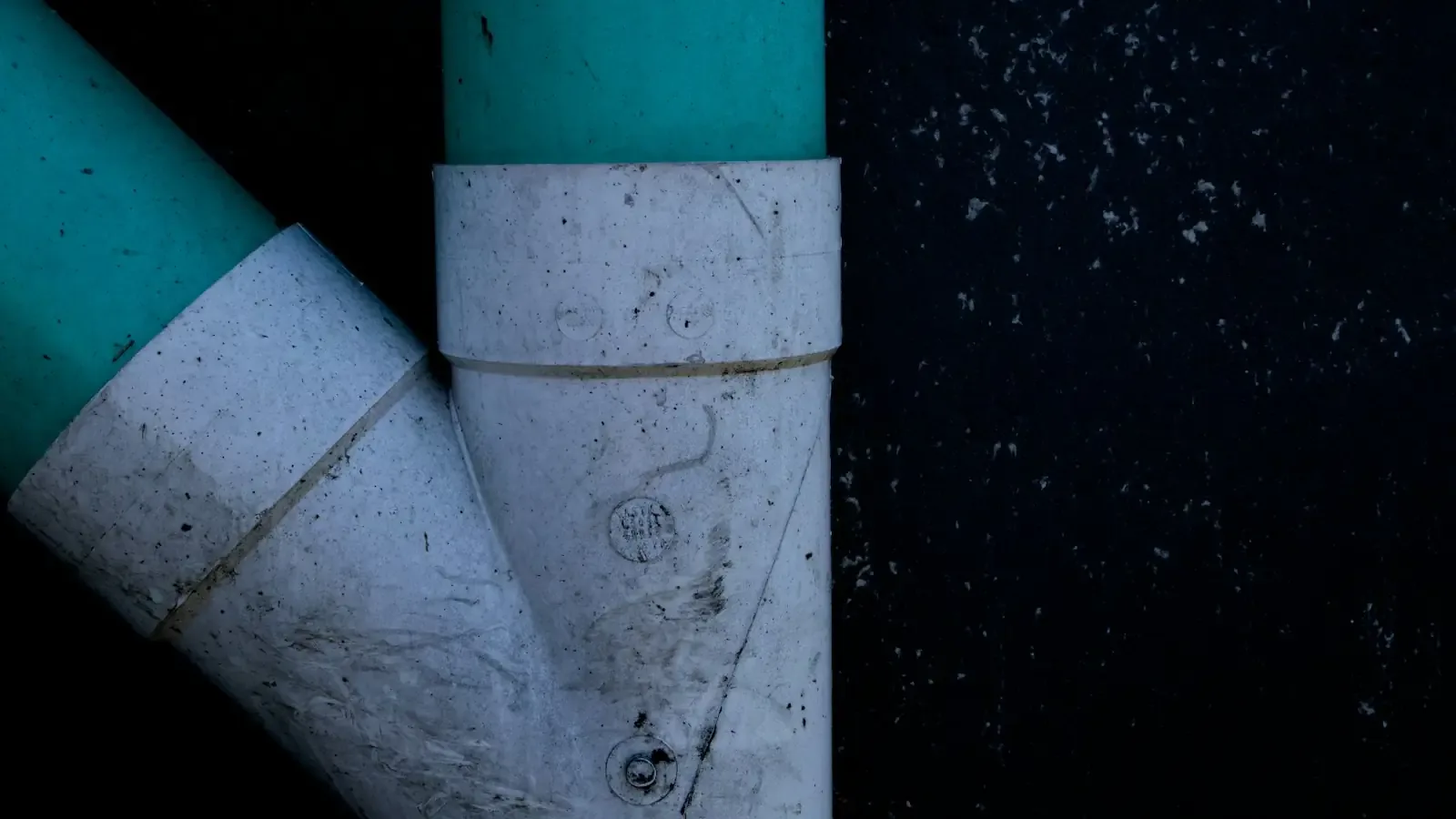 A white plastic wye fitting joining two pipes